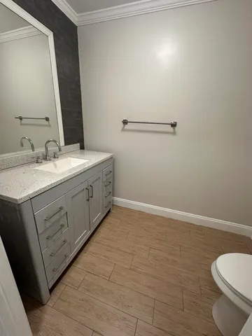 a bathroom with a granite countertop sink a toilet and a mirror
