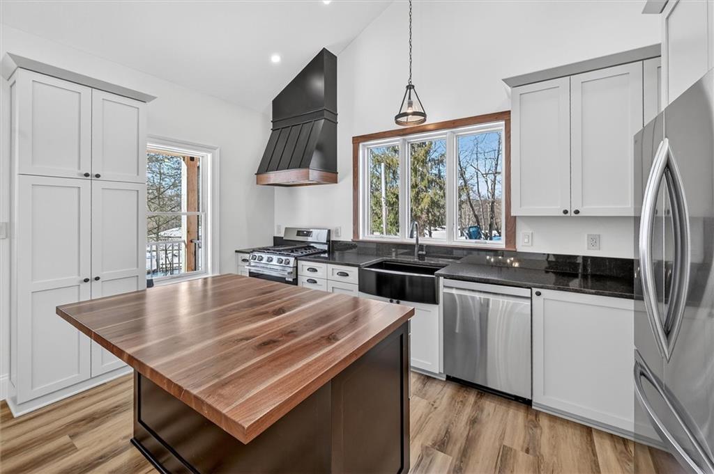 392 Stuber Road Beaver Falls, PA 15010 - Photo 13 of 48 a kitchen with stainless steel appliances granite countertop a stove a sink dishwasher and a refrigerator with wooden floor