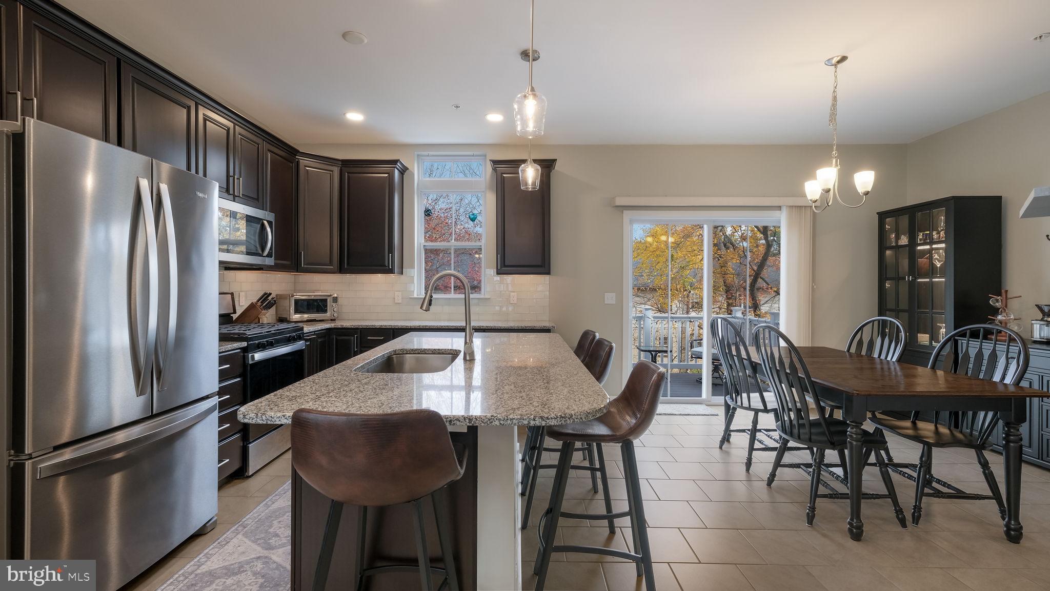 42 Independence Court Perkasie, PA 18944 - Photo 8 of 23 a kitchen with granite countertop a refrigerator a stove a dining table and chairs