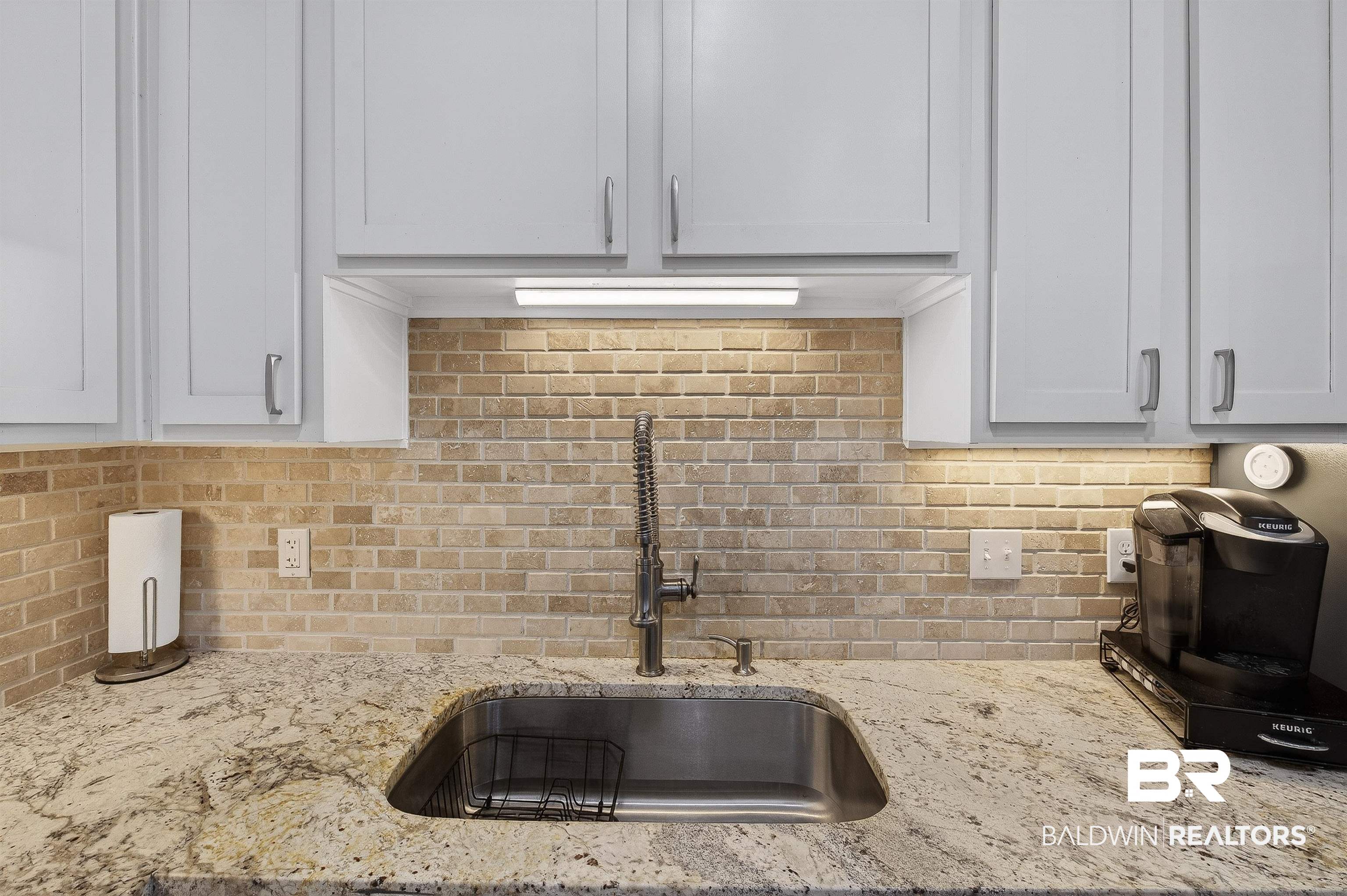 1430 West Regency Road, Unit I102 Gulf Shores, AL 36542 - Photo 9 of 31 Kitchen featuring light stone counters, decorative backsplash, and white cabinets
