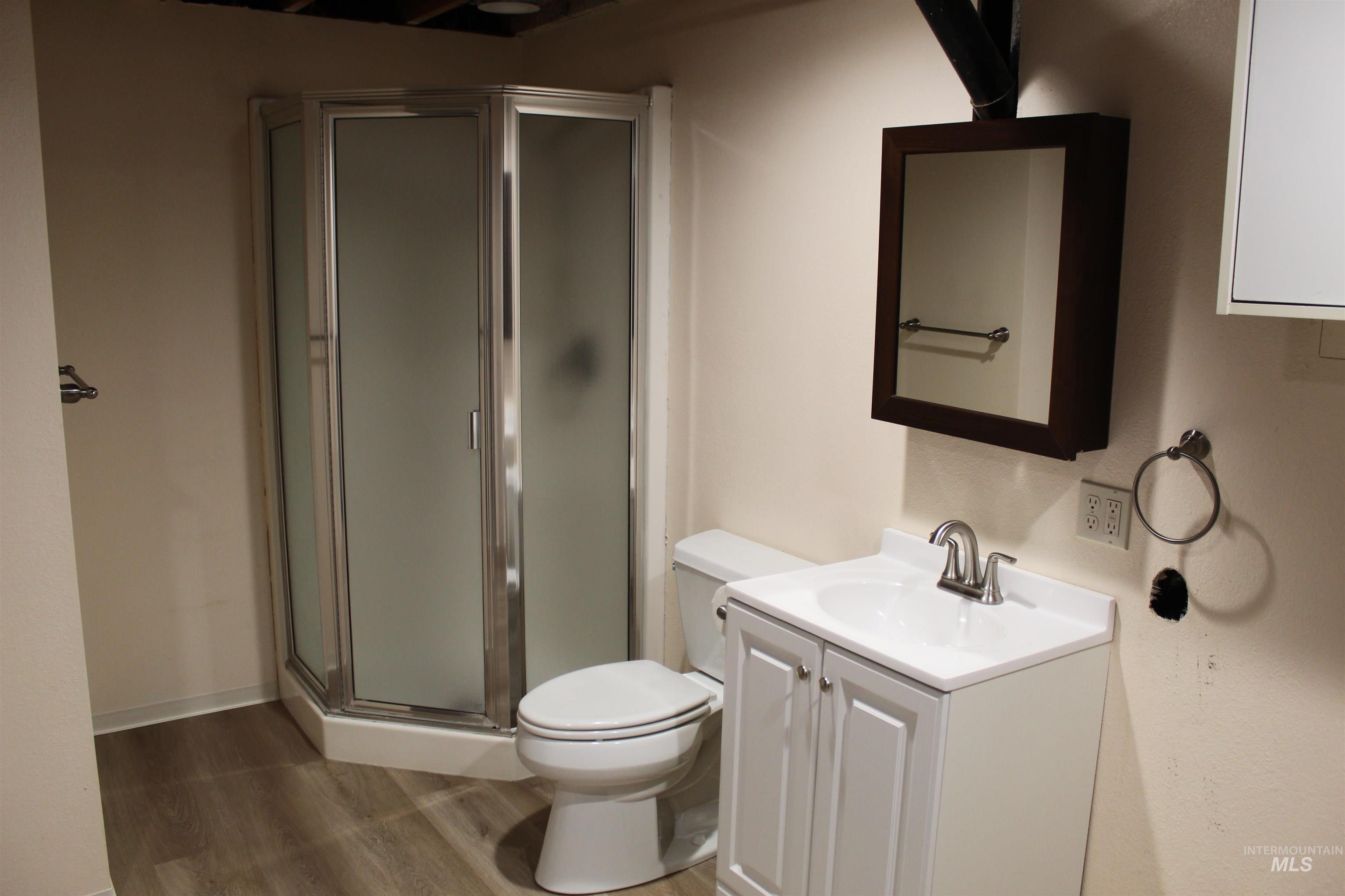 85 Northwest 16th Street Ontario, OR 97914 - Photo 14 of 25 Full bathroom featuring vanity, a shower stall, and dark wood-style floors
