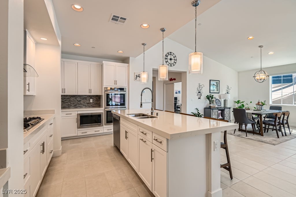 130 West Fairway Road Henderson, NV 89015 - Photo 12 of 40 Kitchen featuring pendant lighting, backsplash, white cabinetry, recessed lighting, and a kitchen island with sink