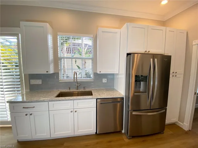 a living room with stainless steel appliances furniture a refrigerator and a kitchen view