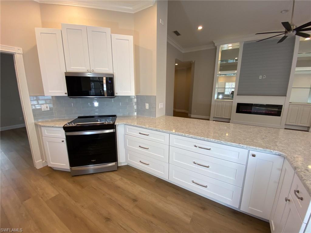 2740 Island Pond Lane Naples, FL 34119 - Photo 5 of 43 a kitchen with granite countertop white cabinets and stainless steel appliances