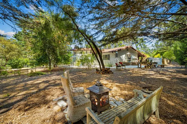 a view of a backyard with table and chairs with wooden fence and plants