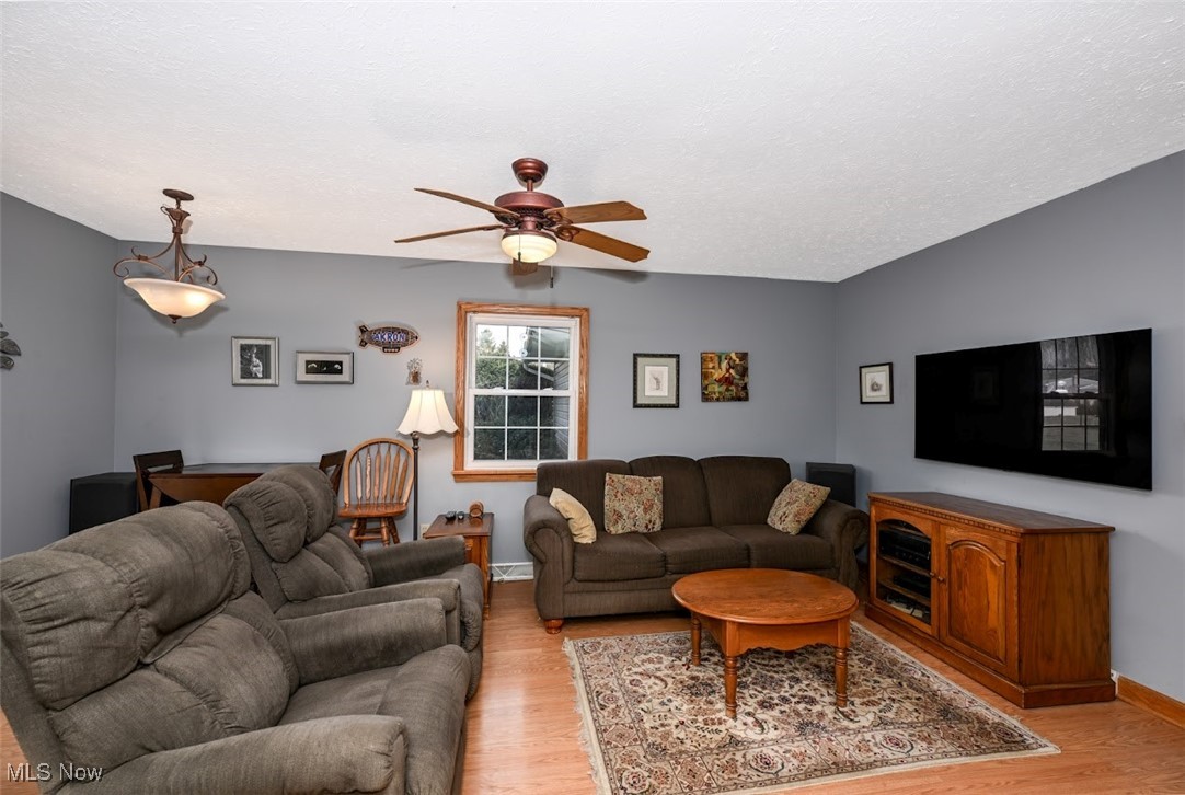 3305 Edington Road Akron, OH 44333 - Photo 15 of 46 Living area with baseboards, a textured ceiling, a ceiling fan, and light wood finished floors