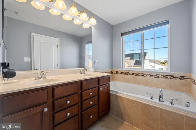 a bathroom with a tub a sink double vanity and a mirror