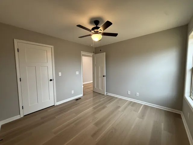 an empty room with a window and a ceiling fan