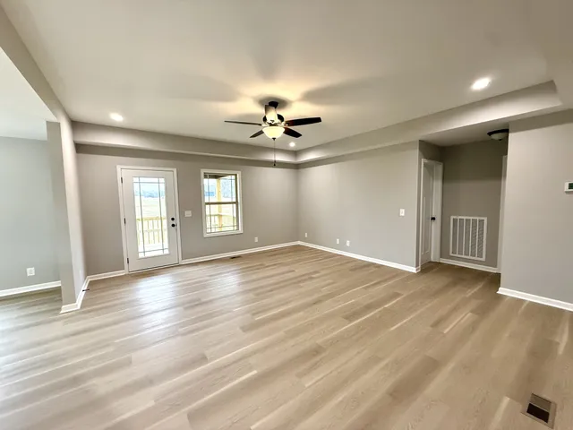 a view of a kitchen with stainless steel appliances kitchen island granite countertop wooden floor and window