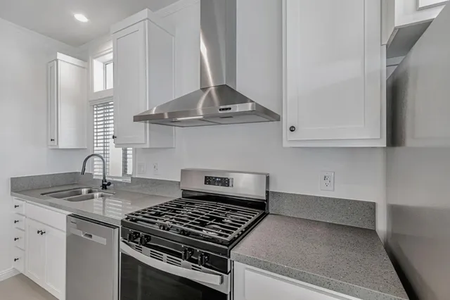 a kitchen with granite countertop a sink stove and cabinets