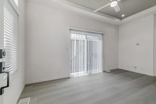 an empty room with wooden floor and windows with curtains