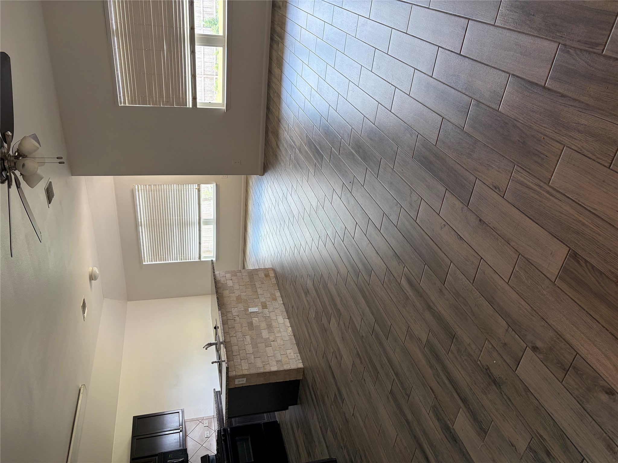 137 Rafe Court Kyle, TX 78640 - Photo 22 of 36 A well-lit, open-concept living space features wood-look tile flooring and a functional kitchen island.