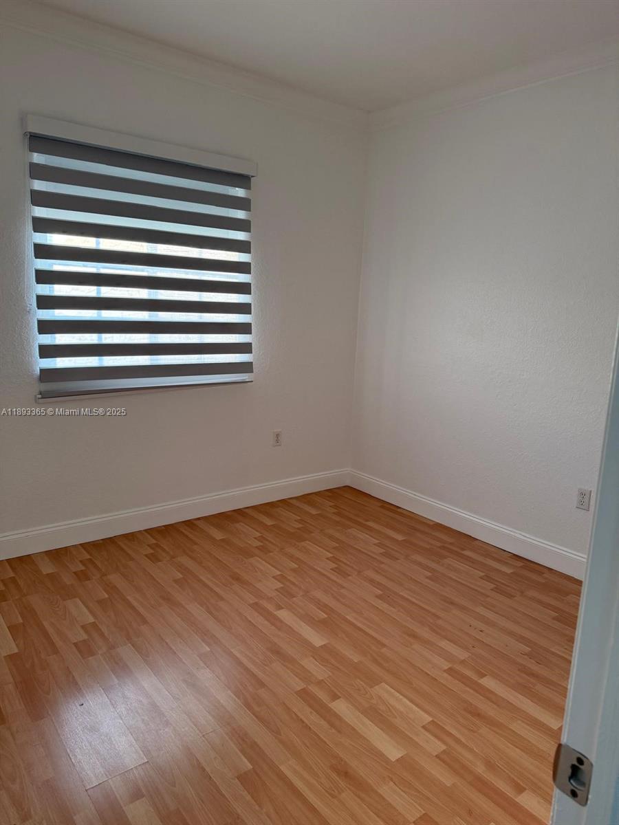 7221 Northwest 174th Terrace, Unit 202 Hialeah, FL 33015 - Photo 11 of 15 a view of empty room with wooden floor and a window