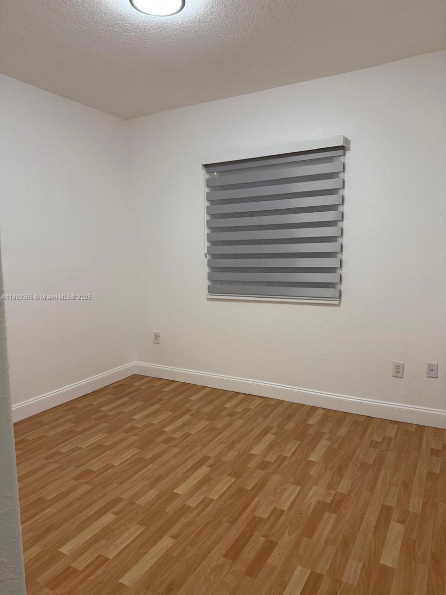 7221 Northwest 174th Terrace, Unit 202 Hialeah, FL 33015 - Photo 10 of 15 a view of an empty room with wooden floor and a window