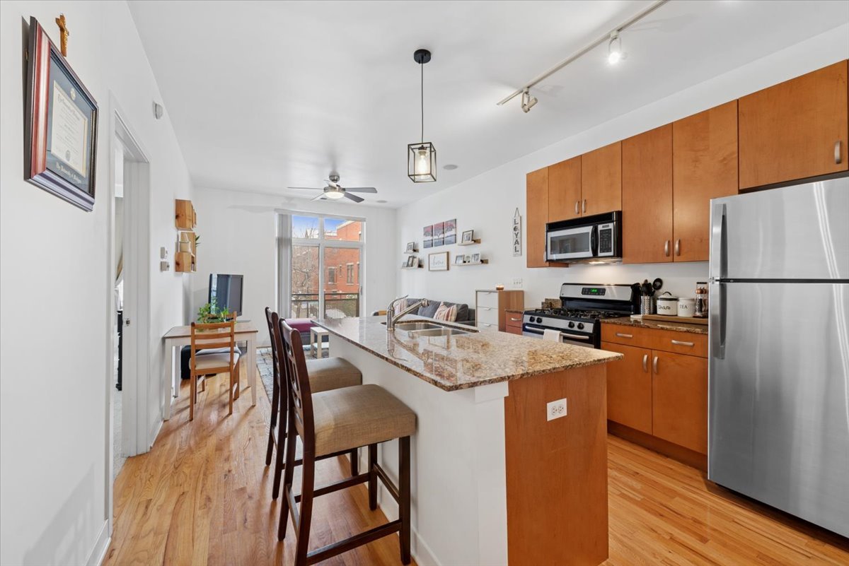 1515 South Halsted Street, Unit 204 Chicago, IL 60607 - Photo 3 of 14 a kitchen with stainless steel appliances granite countertop a refrigerator a stove top oven a sink dishwasher a dining table and chairs with wooden floor