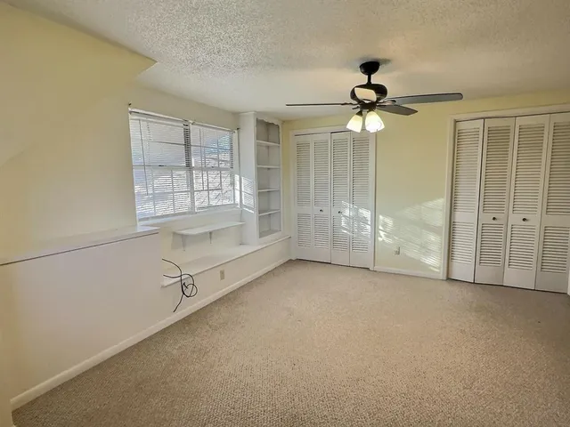 an empty room with windows and fan