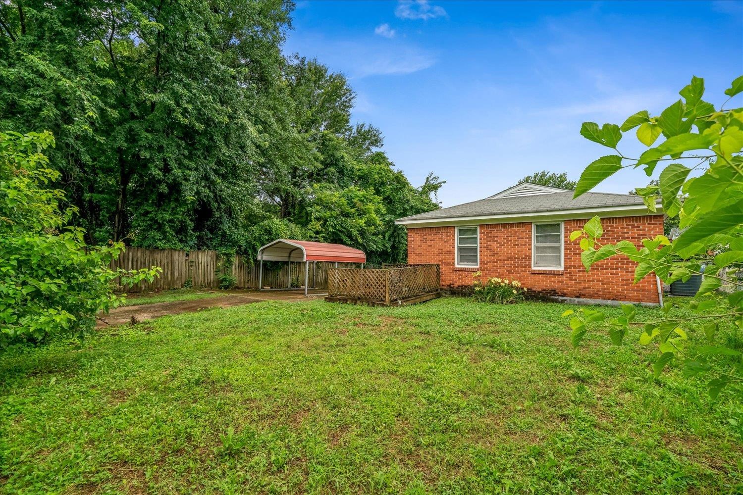 2518 Manchester Road Memphis, TN 38114 - Photo 21 of 23 Expansive backyard featuring a red brick exterior, metal roof, wood deck, and a detached carport