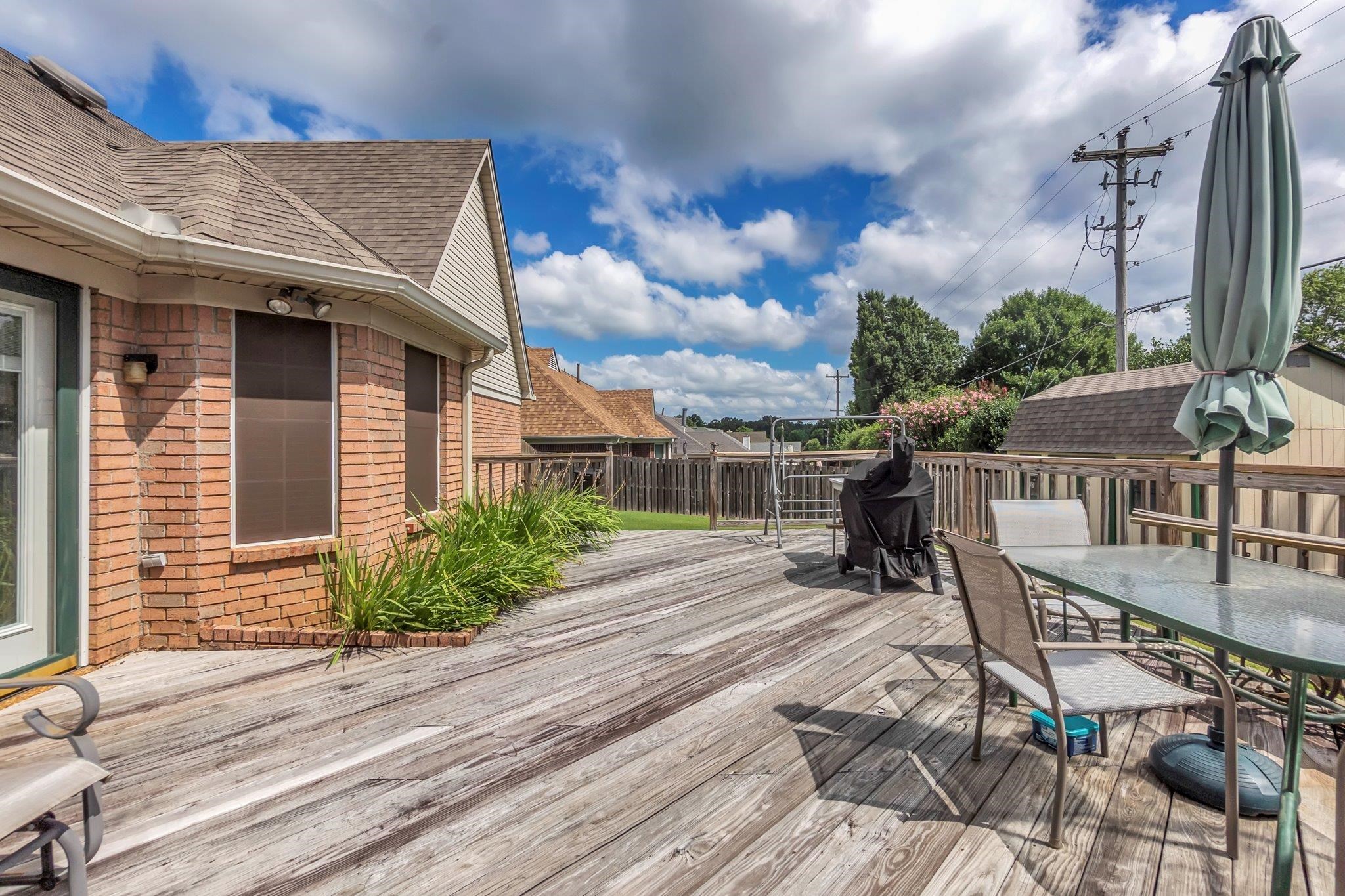 4020 Altruria Road Bartlett, TN 38135 - Photo 24 of 25 Expansive wood deck with a full wood railing, brick exterior, and lush green landscaping