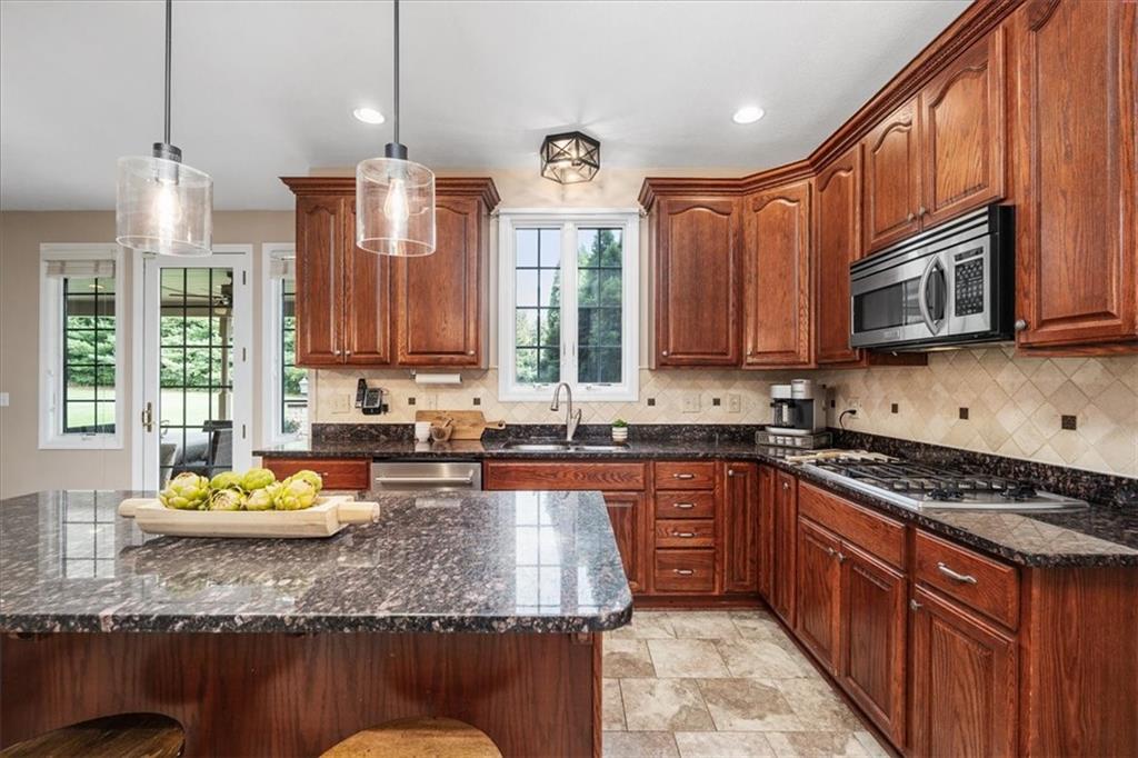 185 Pinkerton Road Wexford, PA 15090 - Photo 11 of 40 a kitchen with stainless steel appliances granite countertop a stove a sink dishwasher and microwave with wooden cabinets