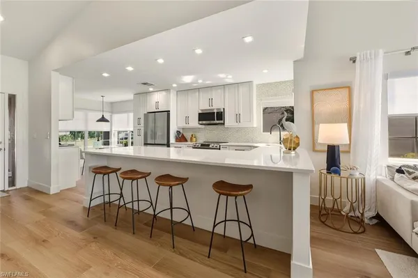 a kitchen with stainless steel appliances granite countertop a table chairs sink refrigerator and cabinets