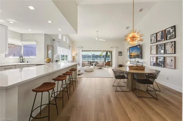 a living room with stainless steel appliances furniture a rug kitchen view and a chandelier