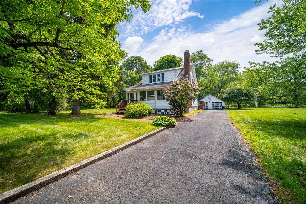 View of front of house with an outbuilding, a chimney, a garage, and a front yard