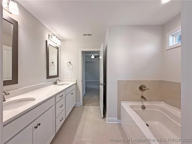 a bathroom with a tub double sink and mirror