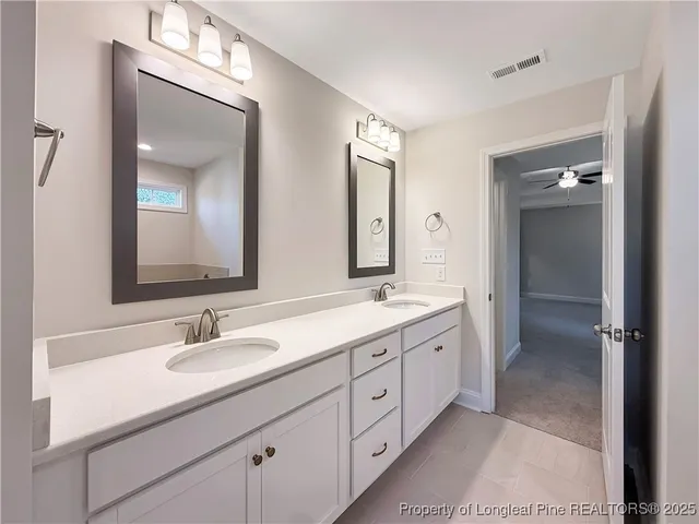 a bathroom with a double vanity sink mirror and next to a refrigerator