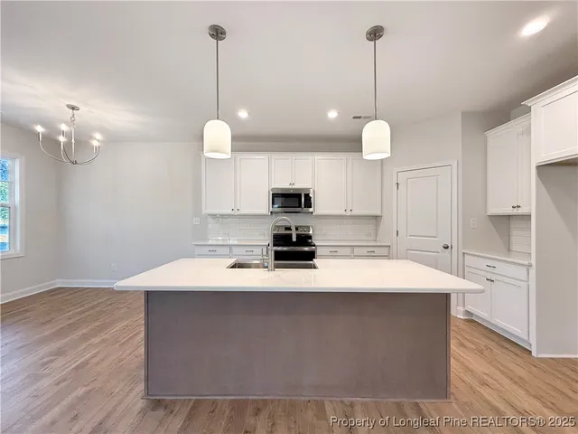 a large kitchen with a refrigerator a stove a sink a dining table and chairs