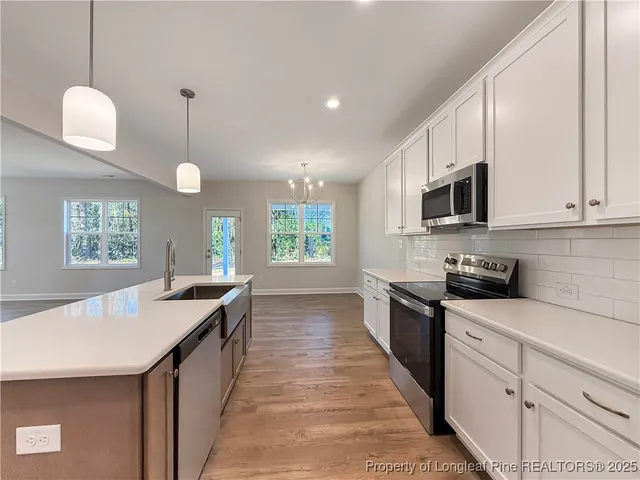 a kitchen with stainless steel appliances kitchen island granite countertop a sink a stove top oven a counter space and cabinets