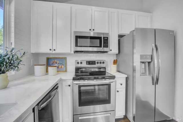 a kitchen with stainless steel appliances white cabinets and a stove top oven
