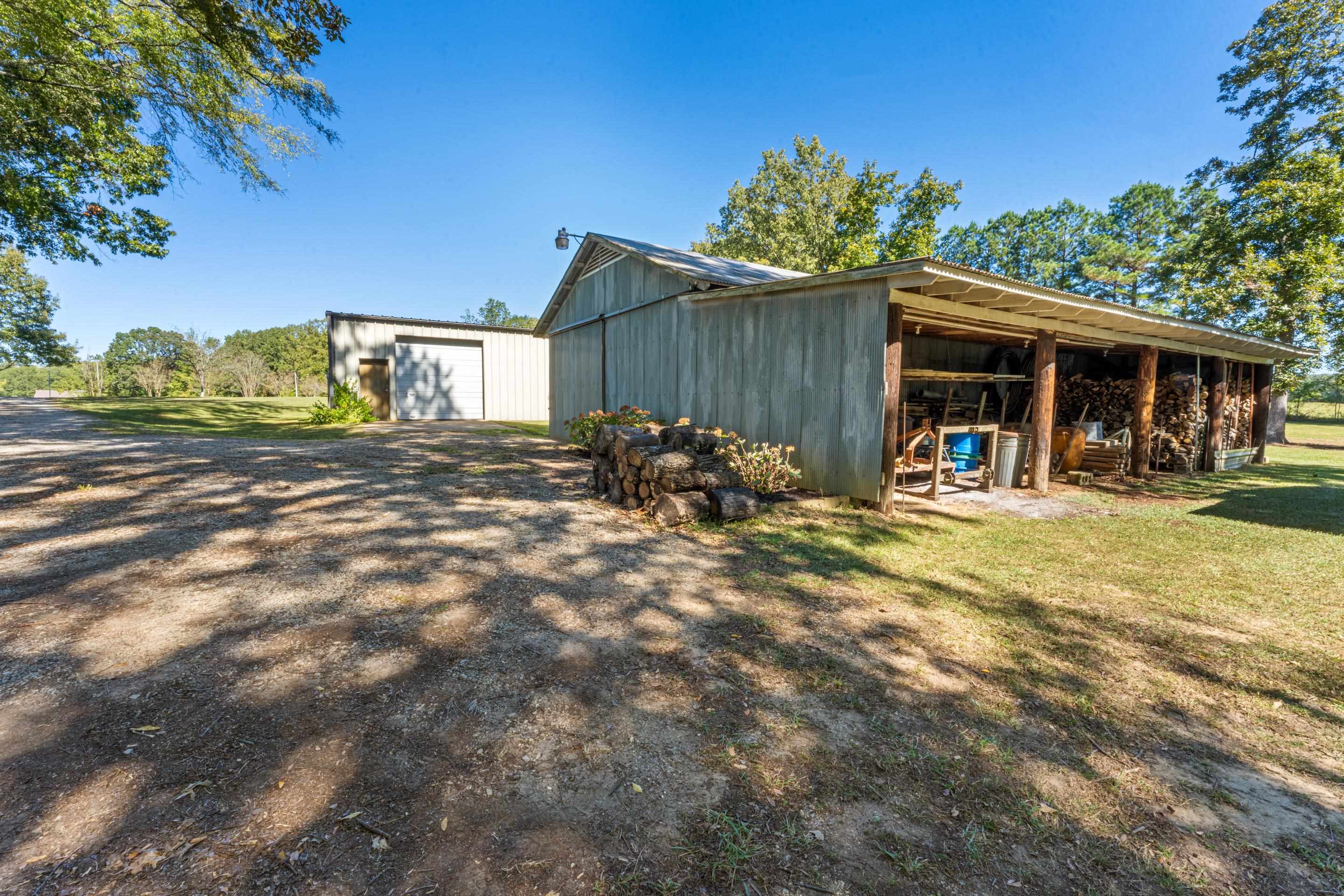 650 Blain Road Rossville, TN 38066 - Photo 26 of 26 The large shop and smaller barn/shop with covered lean-to provide a variety of functional spaces for work and storage. This exterior perspective emphasizes the property’s flexibility, utility, and connection to the surrounding land.