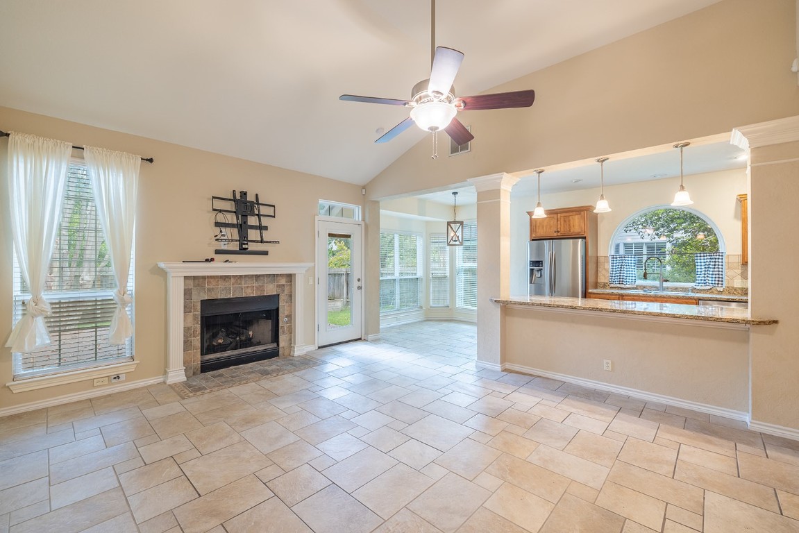 8514 Racine Trail Austin, TX 78717 - Photo 14 of 33 Unfurnished living room with lofted ceiling, a tile fireplace, and a ceiling fan
