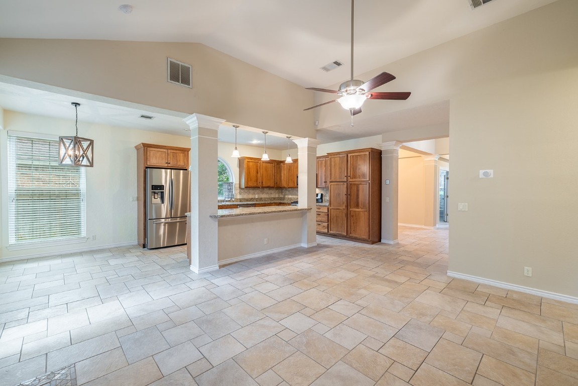 8514 Racine Trail Austin, TX 78717 - Photo 2 of 33 Kitchen featuring brown cabinetry, decorative columns, hanging light fixtures, stainless steel fridge, and a ceiling fan