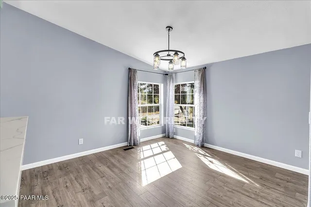 a view of empty room with wooden floor and window