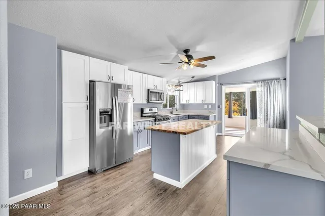 a kitchen with stainless steel appliances granite countertop a refrigerator a sink dishwasher a stove with wooden floor and cabinets