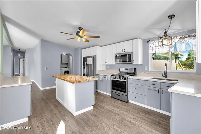 a kitchen with stainless steel appliances a stove top oven a sink dishwasher a dining table and chairs with wooden floor