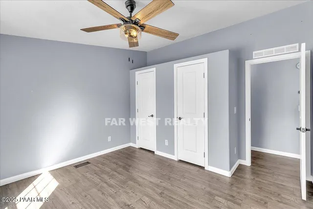 an empty room with wooden floor closet and fan chandelier fan