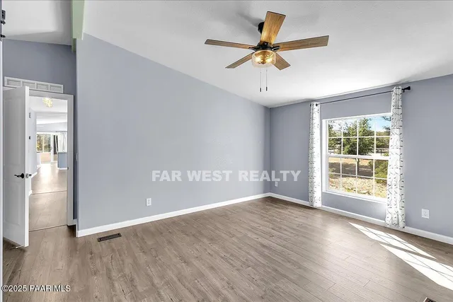 a view of an empty room with a window and wooden floor