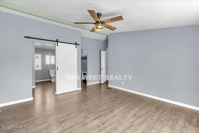 an empty room with wooden floor and a ceiling fan