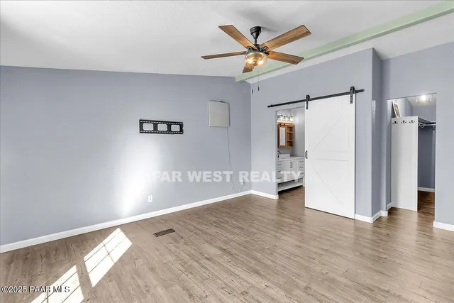 a view of a hallway with wooden floor and a ceiling fan