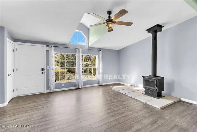 a view of an empty room with a window and wooden floor