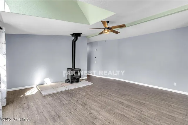 a view of a room with wooden floor ceiling fan and windows