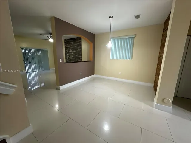 an empty room with kitchen view and natural light