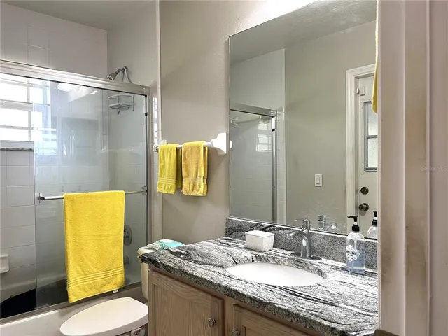 a bathroom with a granite countertop sink toilet and mirror