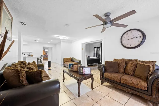 a living room with furniture a clock and a ceiling fan
