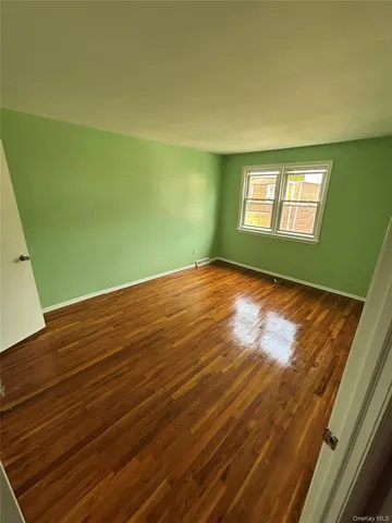 a view of empty room with window and hardwood floor