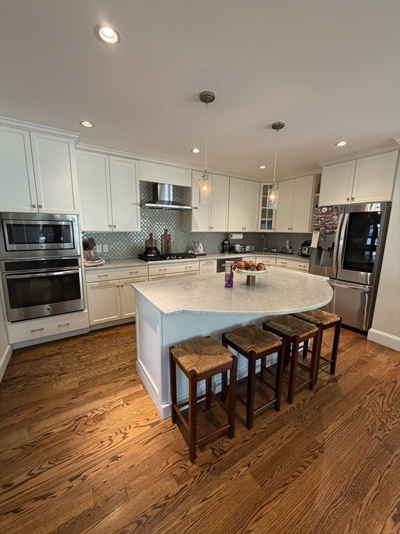 17 Cardinal Street, Unit 17 Winchester, MA 01890 - Photo 9 of 42 a kitchen with stainless steel appliances granite countertop a stove top oven a sink dishwasher a dining table and chairs with wooden floor