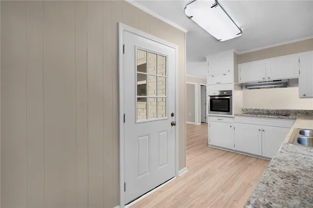 a kitchen with granite countertop a refrigerator a stove a sink and white cabinets with wooden floor