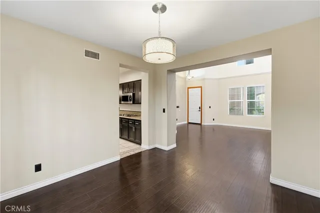 a view of a room with wooden floor chandelier and windows